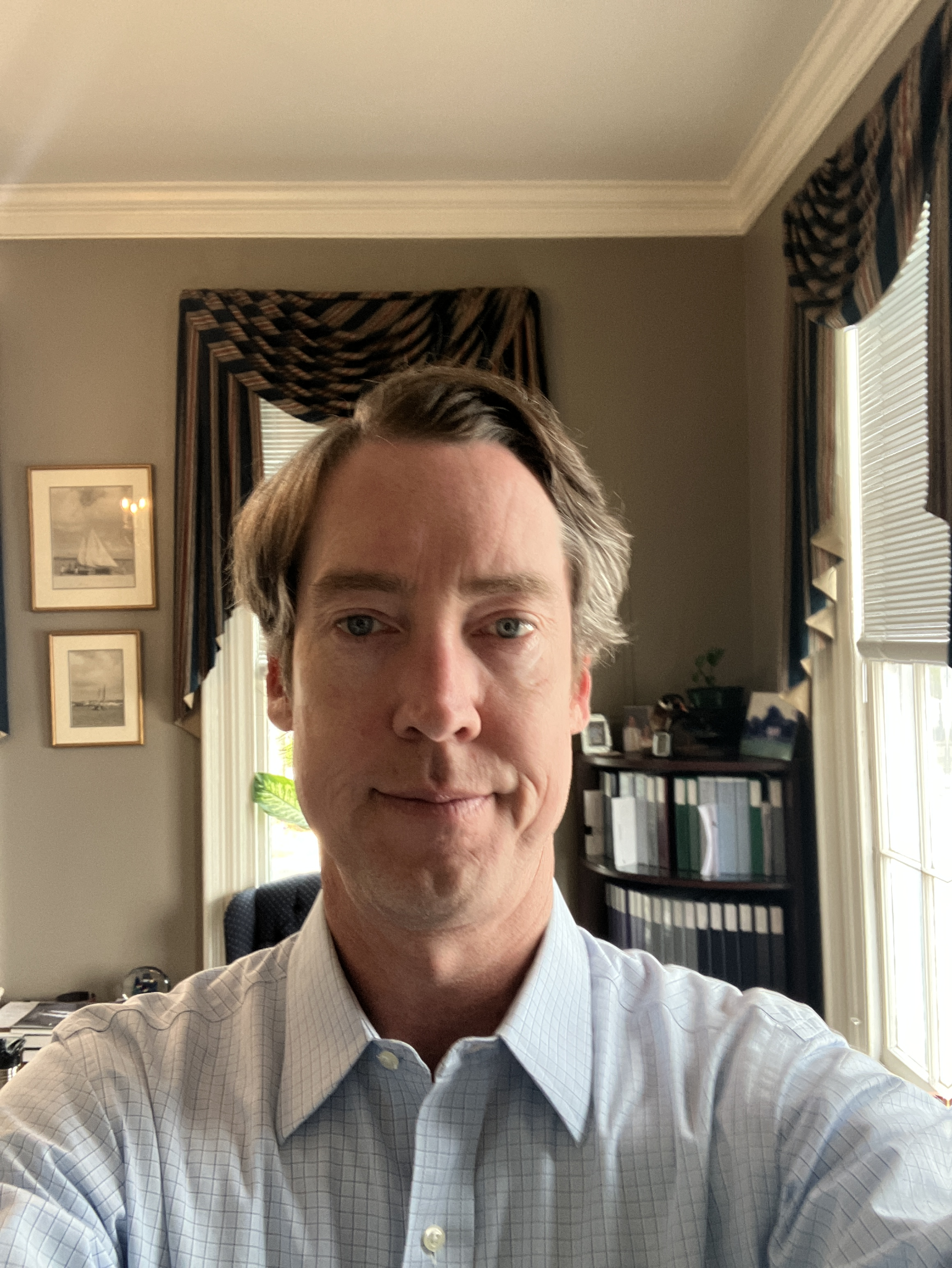 An office portrait with tall windows and bookshelves.